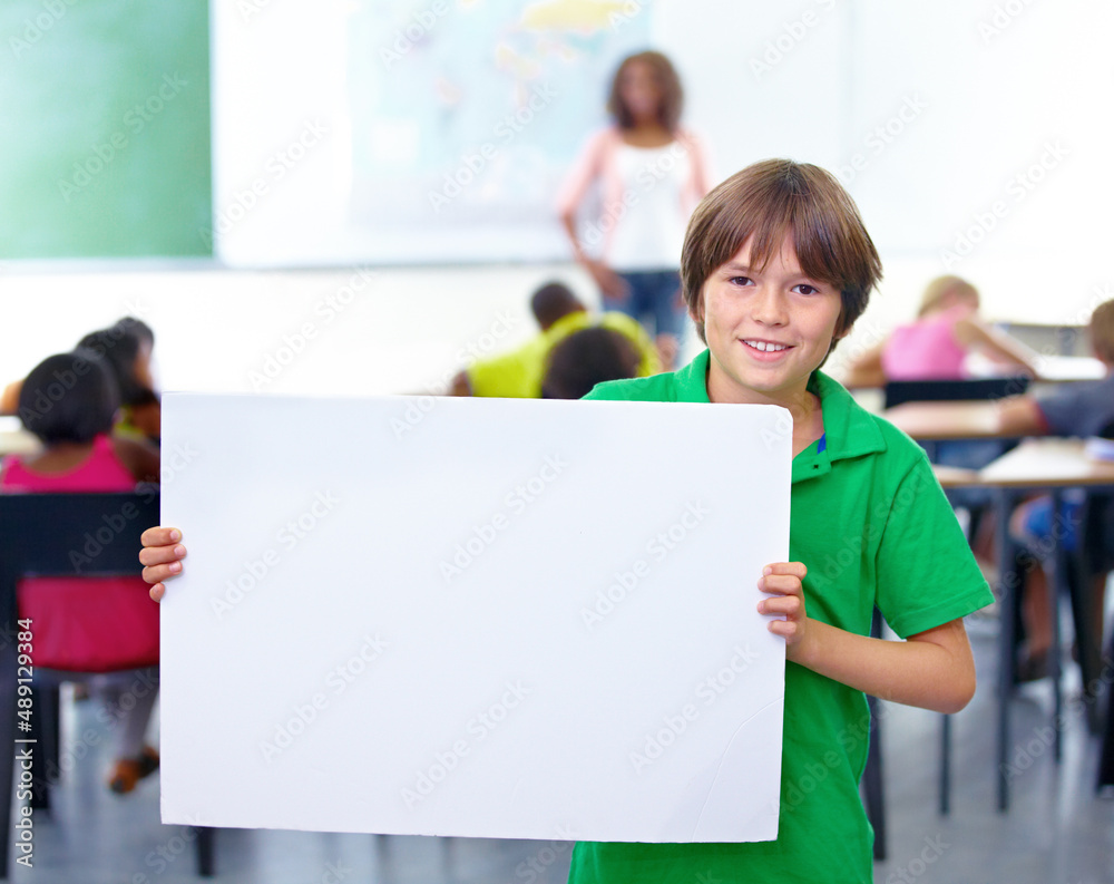 Heres what I think. Portrait of a young schoolboy holding up your copyspace in class.