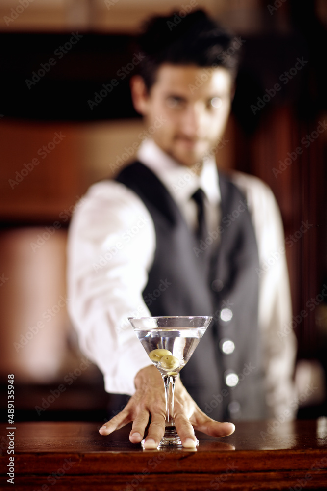 For you. Portrait of a handsome young bartender mixing a cocktail for a customer.