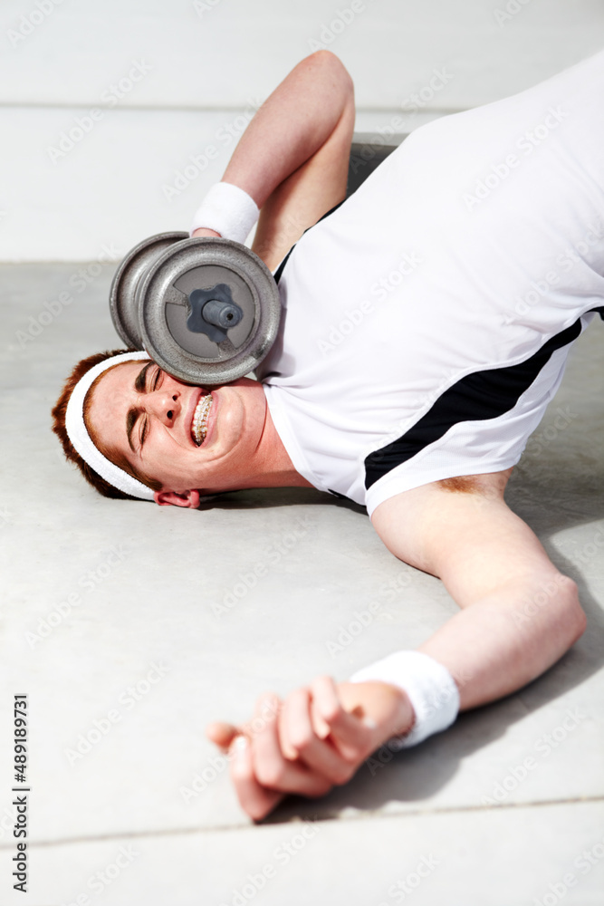 The weight of expectation is too great. A young man trying to lift some heavy weights at the gym and