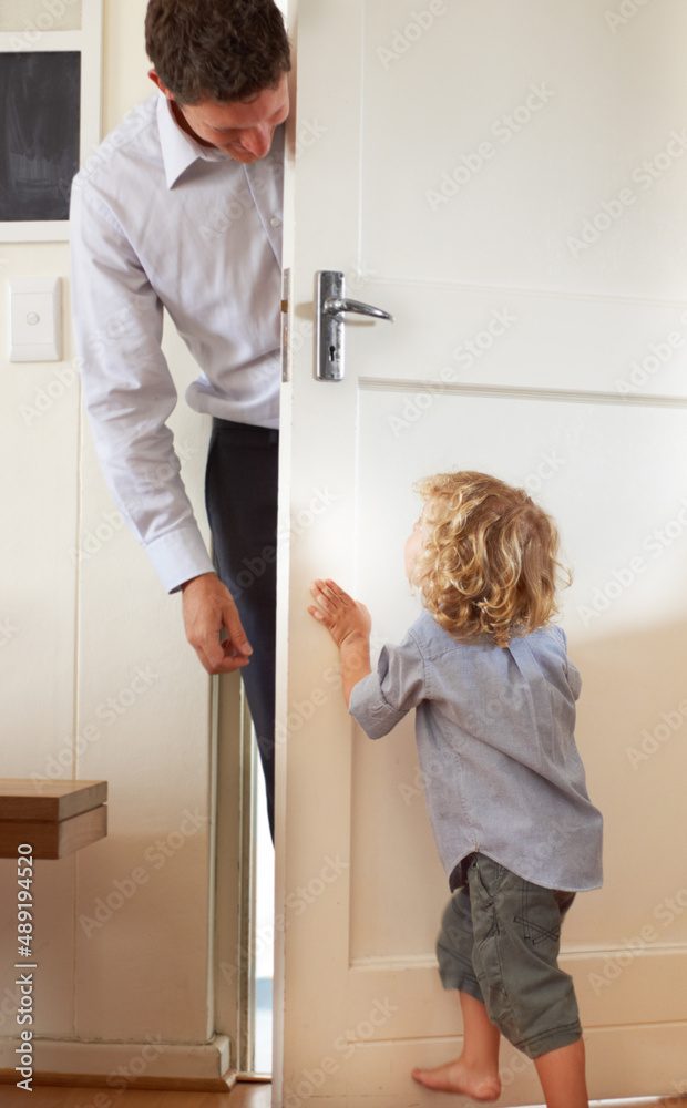 Playing peekaboo. A little boy playfully push a door closed while his father stands on the other sid