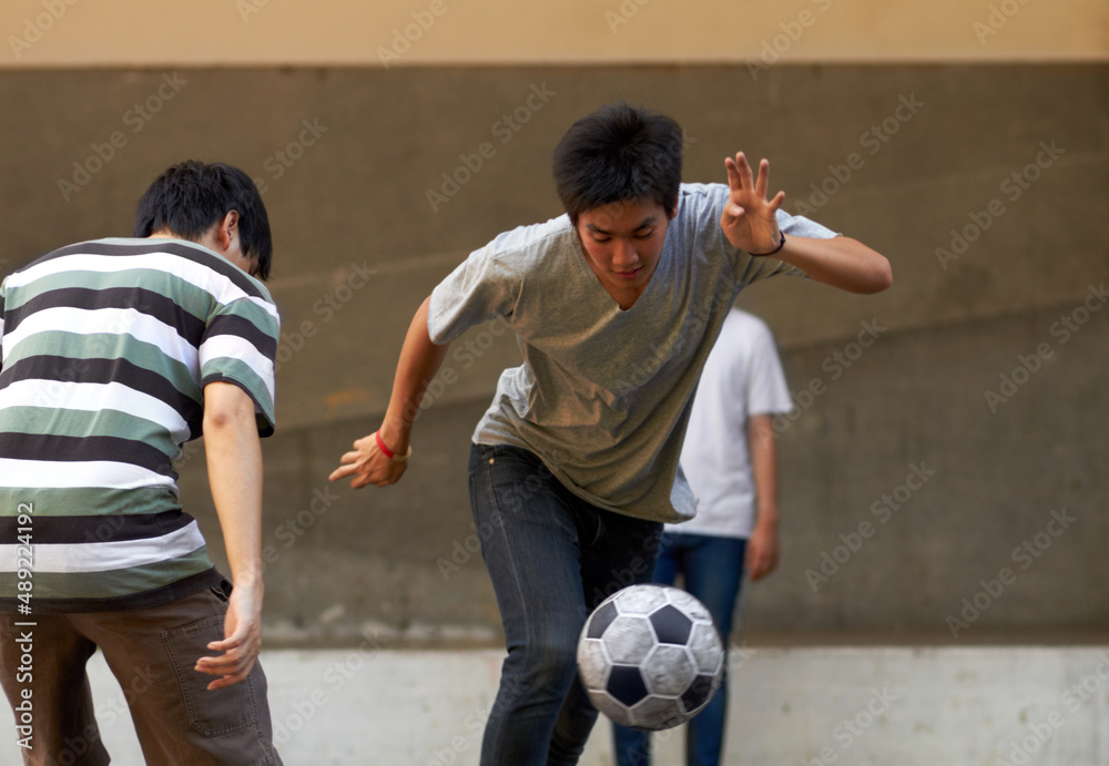 运球冲向球门。年轻的亚洲男子在外面踢足球。