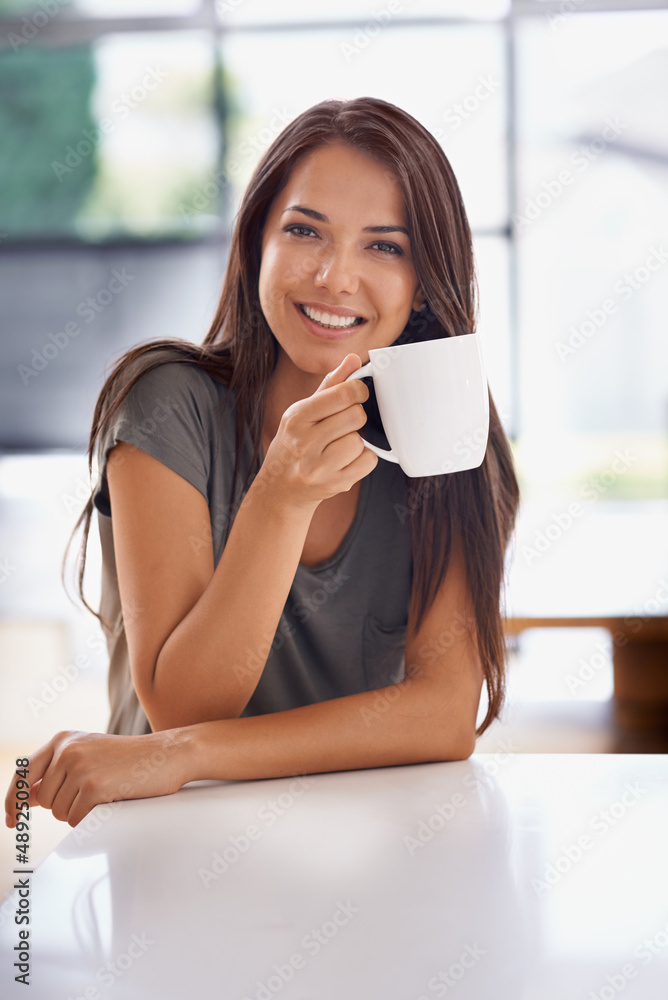 Relaxing with a cup of java. Shot of an attractive young woman drinking a coffee at home.