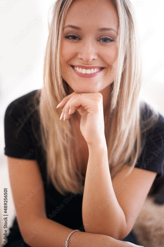 Her smile puts everyone at ease. Portrait of a young woman sitting with her hand on her chin.