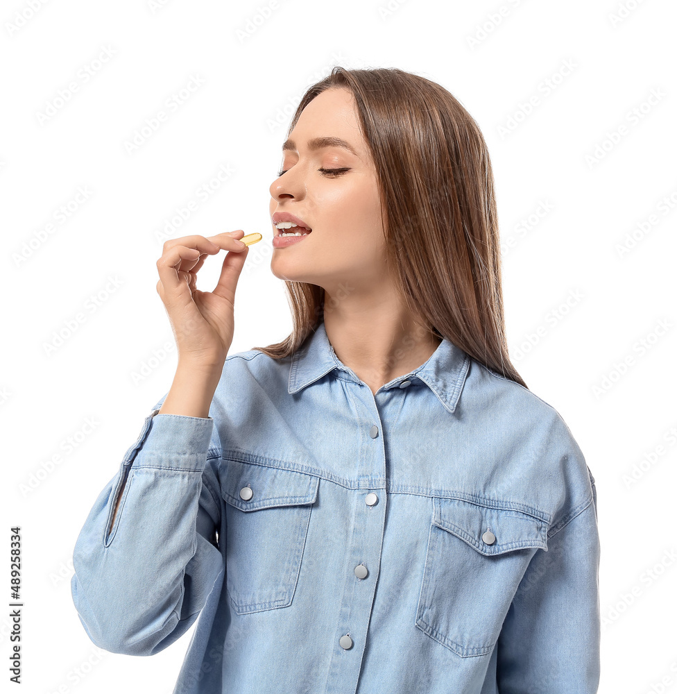 Young woman with healthy fish oil pill on white background