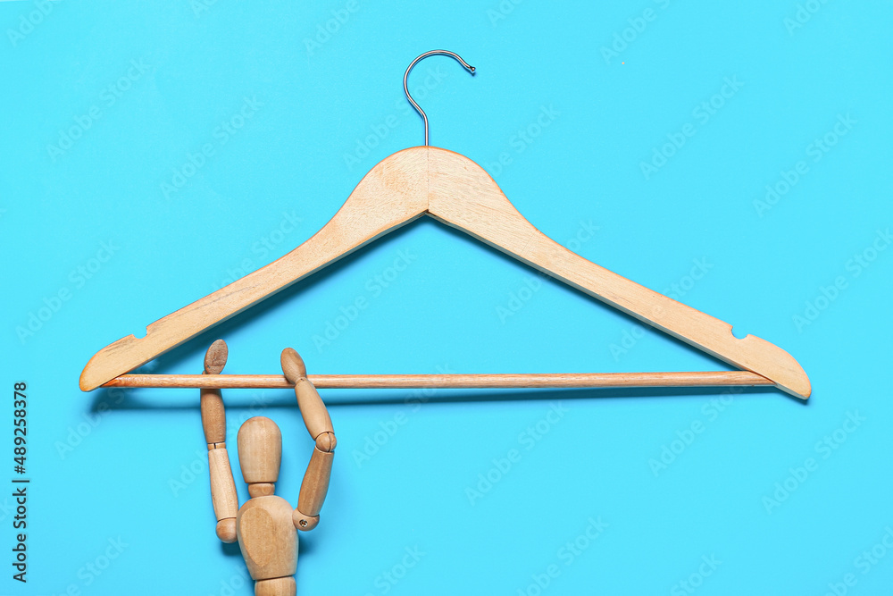 Wooden clothes hanger with mannequin on color background