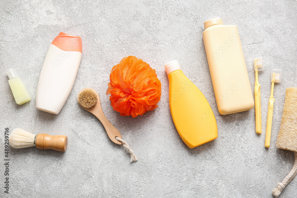 Bottles of cosmetic products and bath accessories on light background