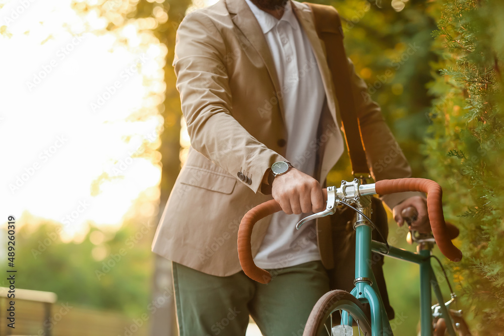 Young businessman with bicycle on city street, closeup