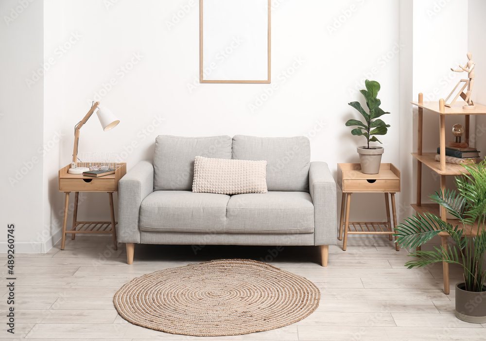 Stylish interior of living room with comfortable sofa, houseplants and wicker carpet