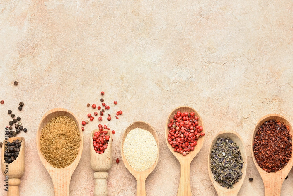 Spoons with aromatic spices on beige background