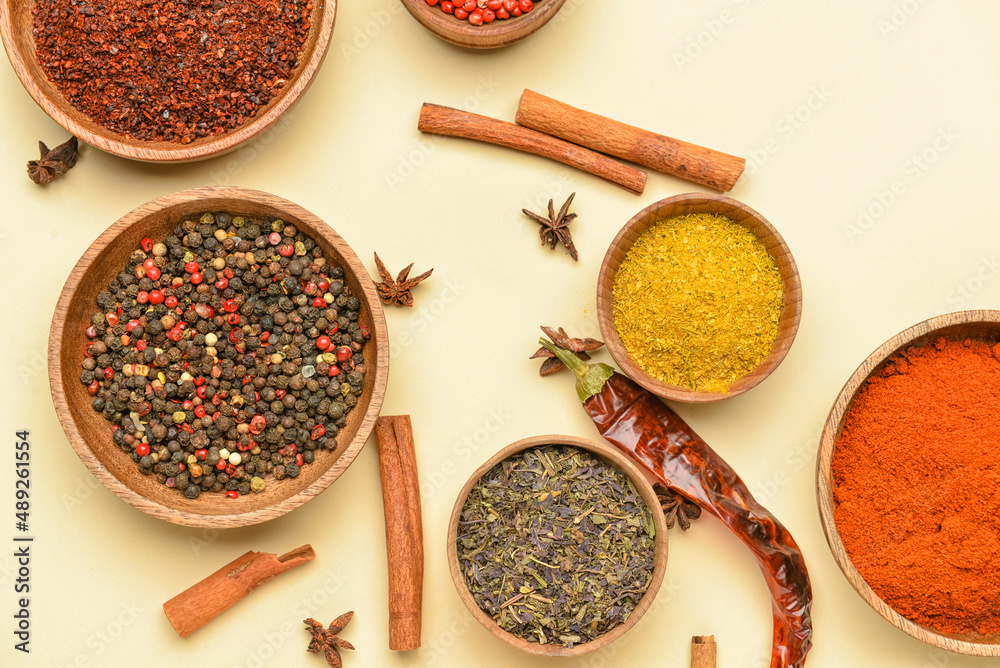 Bowls with aromatic spices on yellow background