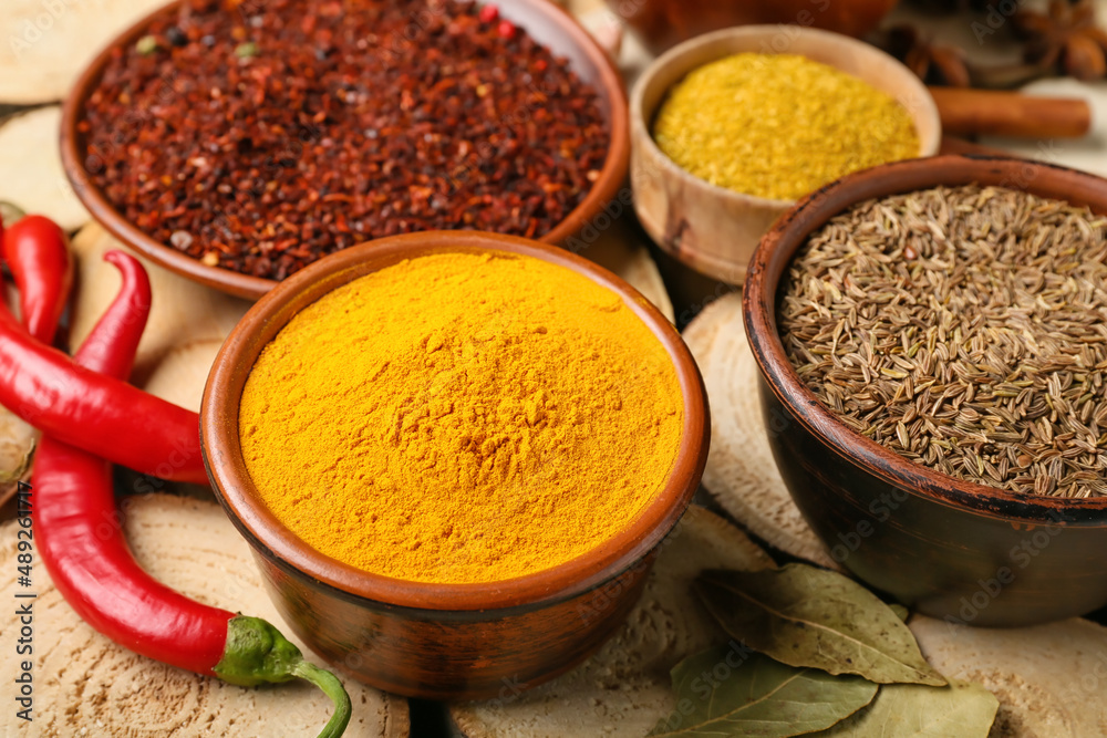 Bowls with aromatic spices on wooden background, closeup