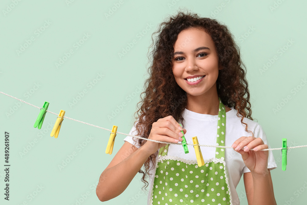 年轻的非洲裔美国妇女在彩色背景上挂衣服