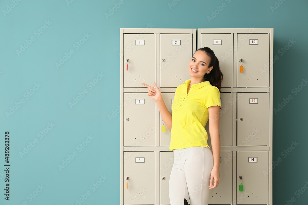 更衣室附近一名运动型年轻女子指着蓝色背景上的东西