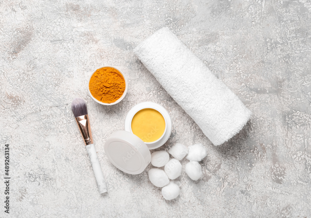 Composition with turmeric mask, powder, cotton and makeup brush on light background