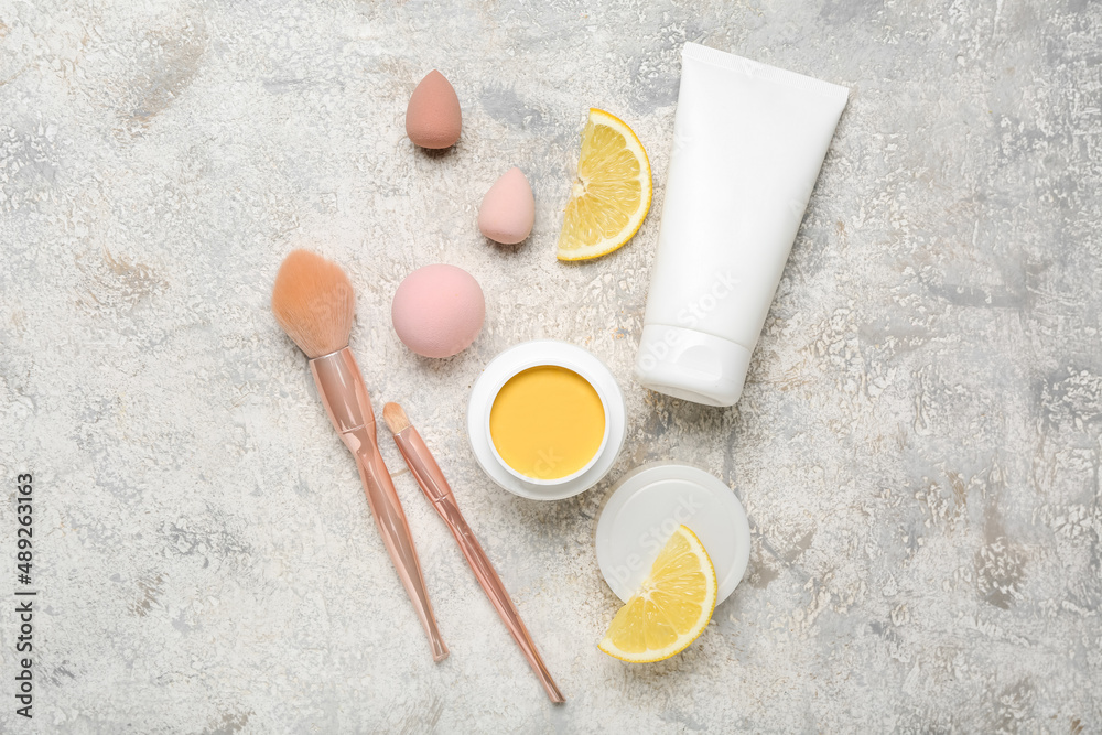 Composition with turmeric mask, makeup brushes, sponges and lemon on light background