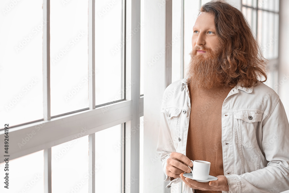 Portrait of handsome bearded man drinking coffee at home