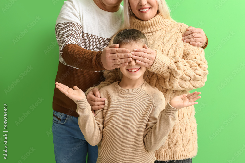 Grandparents closing little boys eyes on green background