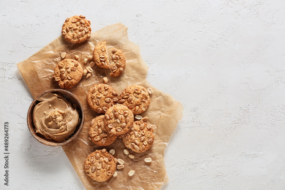 Parchment paper with tasty peanut cookies and butter on white background