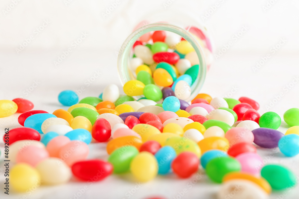 Glass jar with different jelly beans on white background, closeup