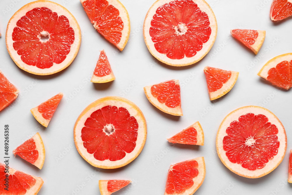 Slices of tasty ripe grapefruit on light background