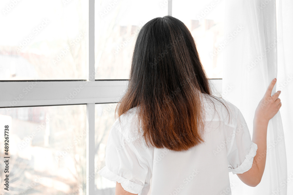 Pretty young Asian woman near window