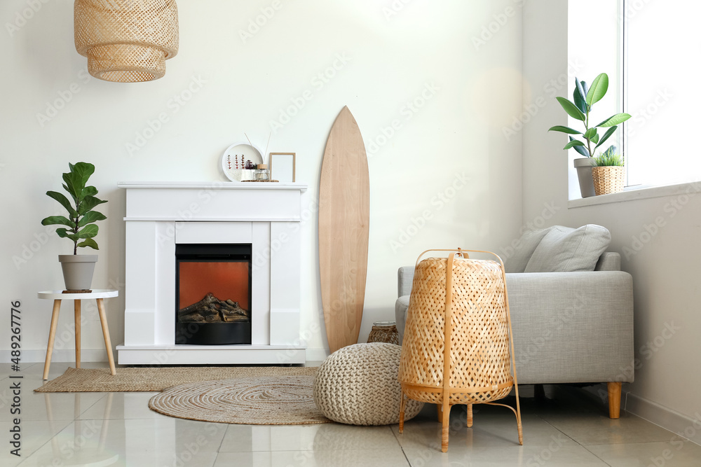 Interior of light living room with wooden surfboard and fireplace