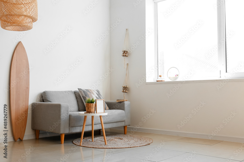 Interior of light living room with wooden surfboard and sofa