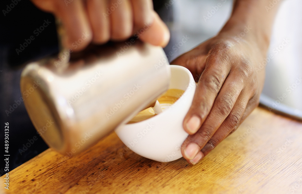 Topping off your cappuccino. Cropped shot of a barista pouring milk froth into a cappuccino.