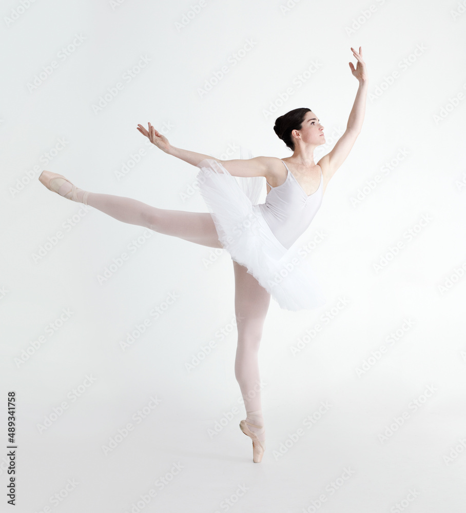 Perfect arabesque. Elegant young ballerina dancing en pointe against a white background.