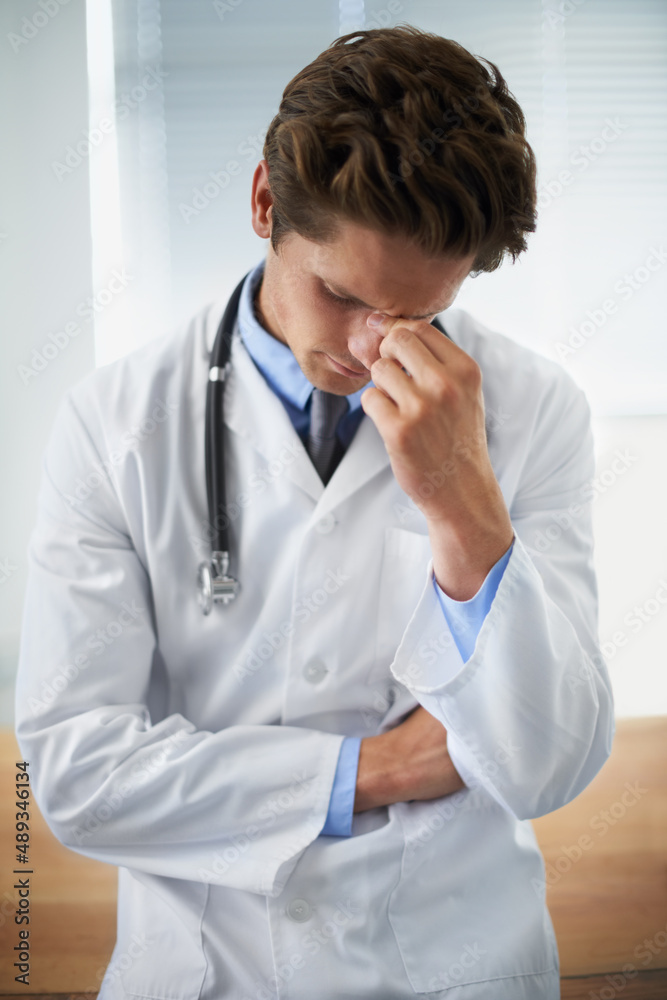 Feeling his patients anguish. Shot of an upset young doctor taking a moment to himself.