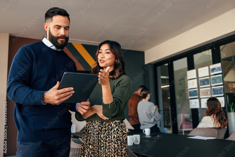 Two businesspeople using a digital tablet in a boardroom