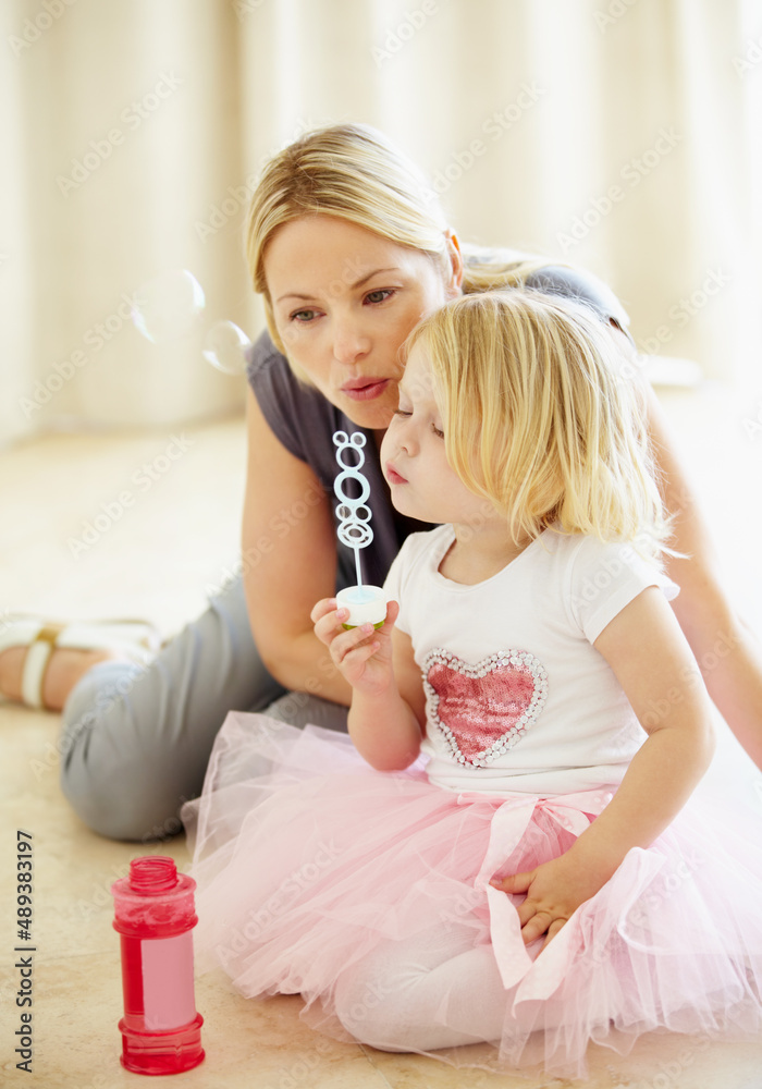 Blowing bubbles with mum. A mother blowing bubbles with her young daughter.