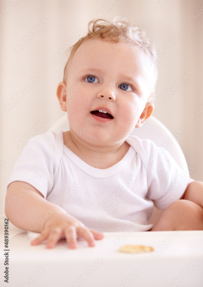 Ready to be fed. A cute baby sitting in a baby chair.