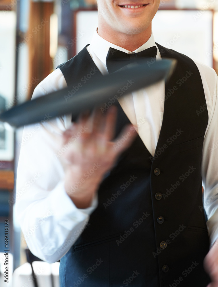 Keeping my customers entertained. Waiter spinning a serving tray on his fingers in a restaurant.