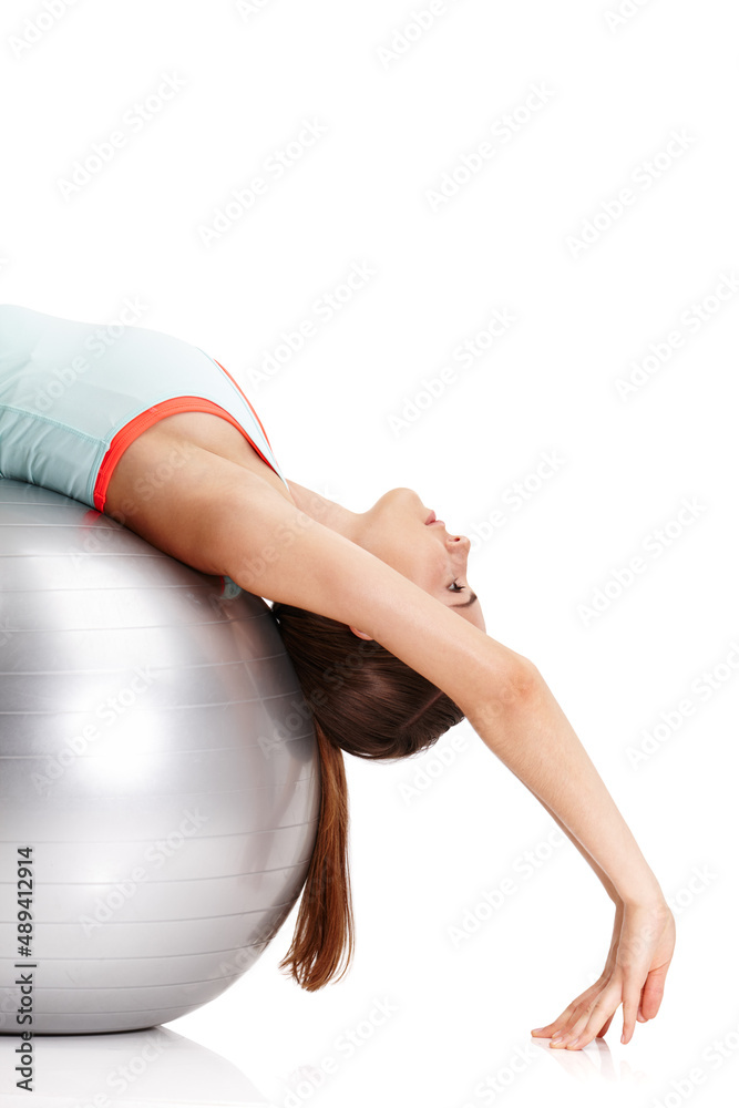 Nothing will work unless you do. Shot of a fit young woman exercising with her exercise ball isolate