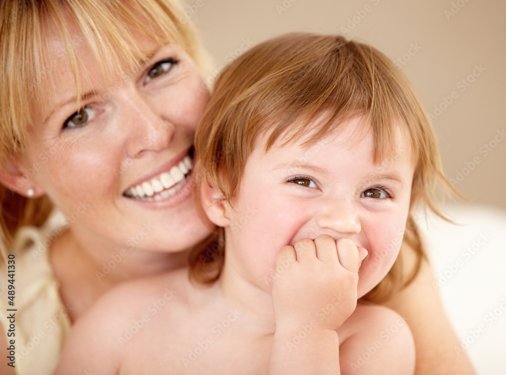 She loves spending time with mom. Smiling mother holding her little girl as she laughs with her hand