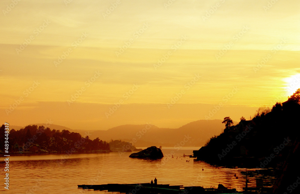 Bathed in gold. A panoramic shot of a lake with small pieces of land, during the sunset with tones o