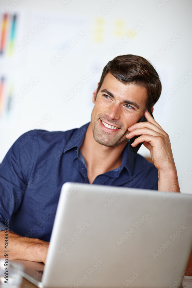 Lost in conversation. Cropped shot of a businessman talking on the phone while working on his laptop