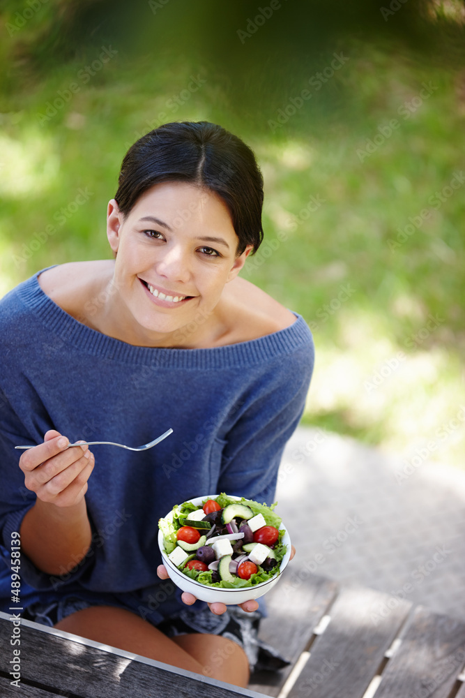 You are what you eat. Cropped shot of an attractive woman sitting in a garden and having a fresh sal