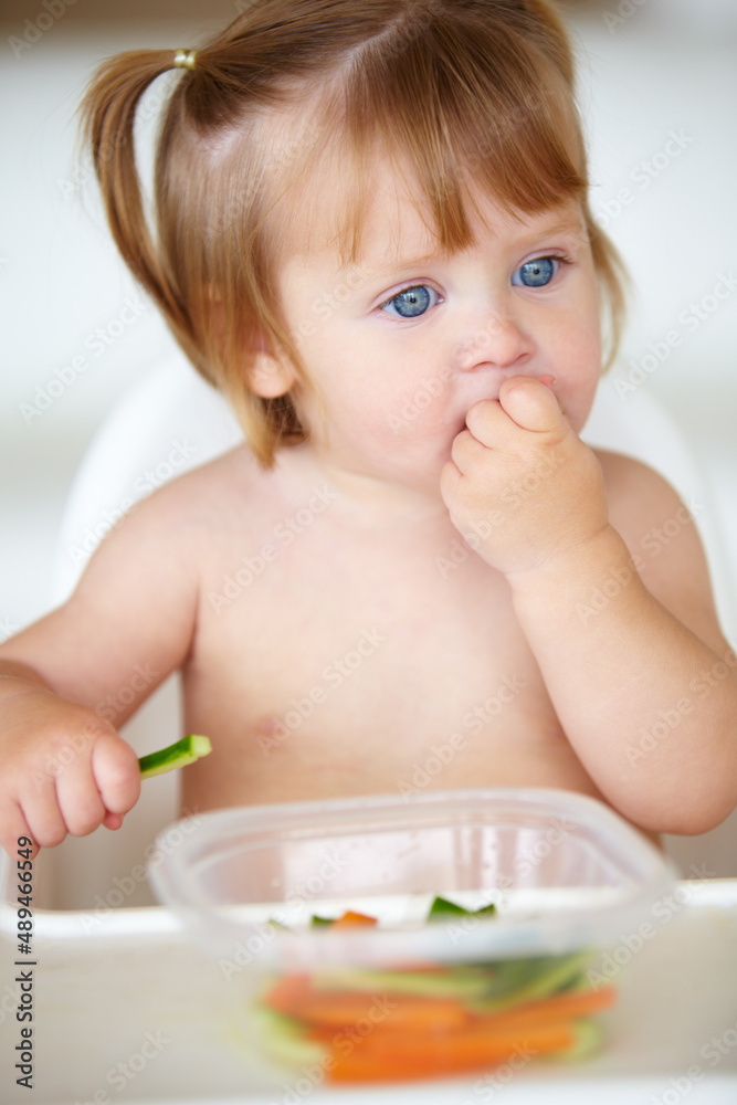 Enjoying veggies from an early age. A cute little girl eating vegetables.