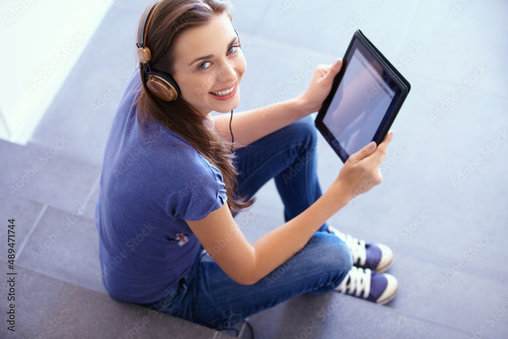 Modern technology. Portrait of an attractive young woman sitting on some steps with her tablet and l