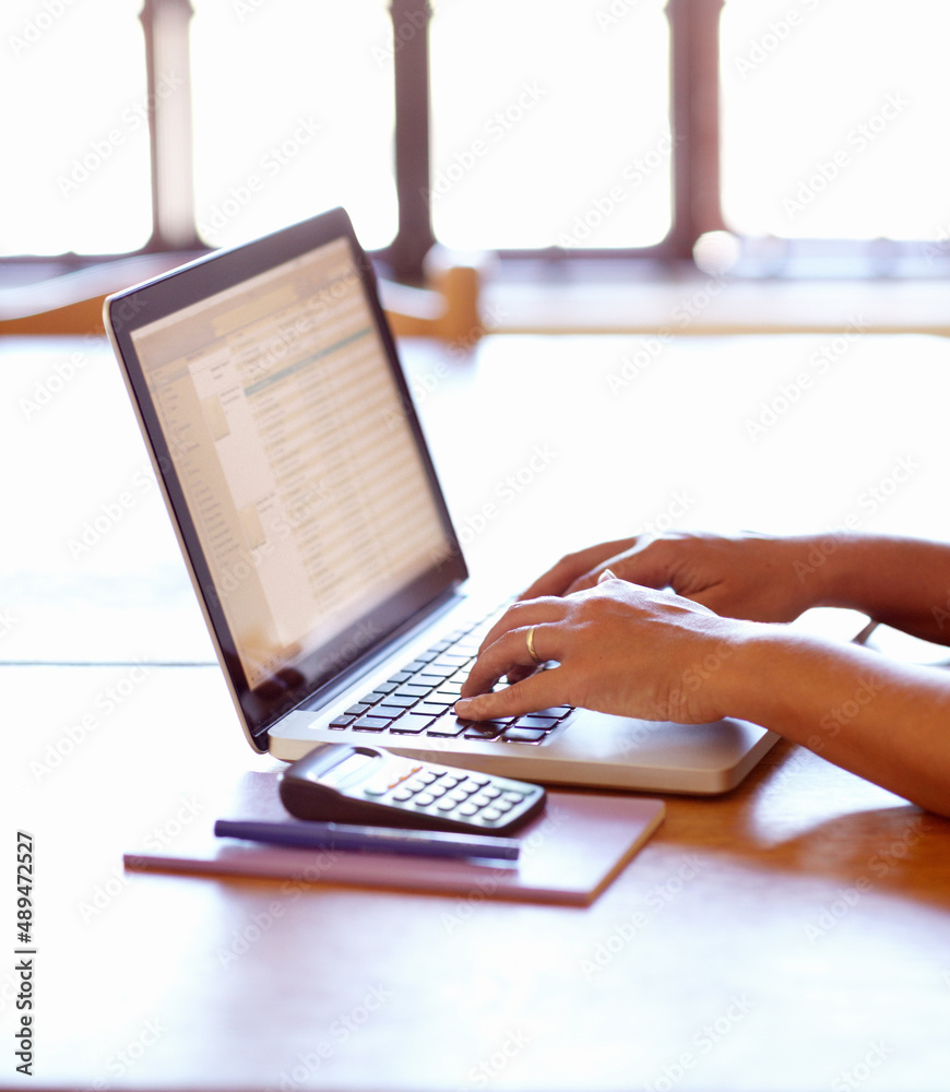 Calculating her tax for the month. Closeup detail view of female hands using a laptop.