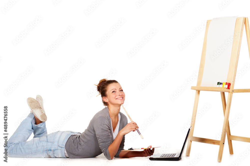 Im looking everywhere for inspiration. Shot of smiling young woman lying down by her laptop and a bl