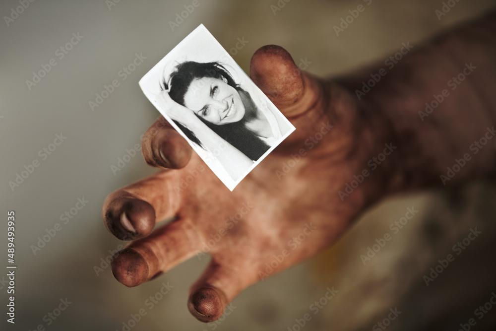 Where is she now. A dirty hand holding a black and white picture of a beautiful woman.