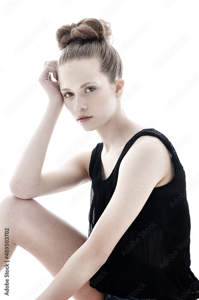 Soft and feminine. Young woman sitting and leaning on her knee isolated on white.