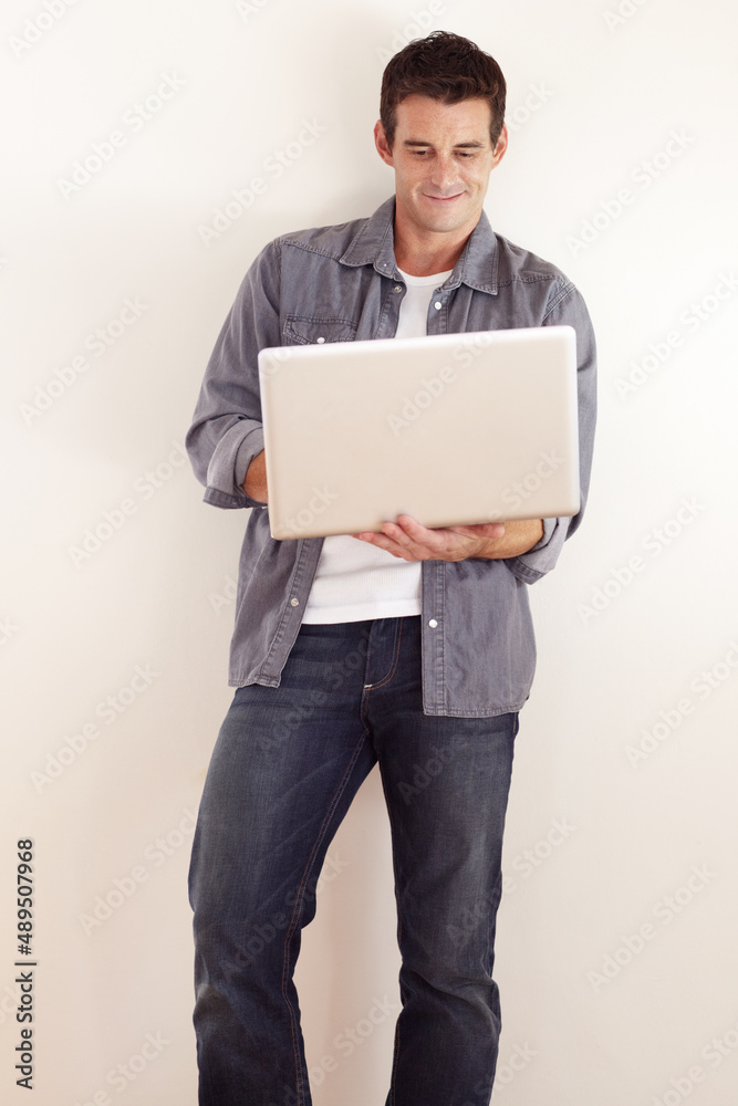 Accessing the internet from anywhere. A handsome young man working on his laptop.