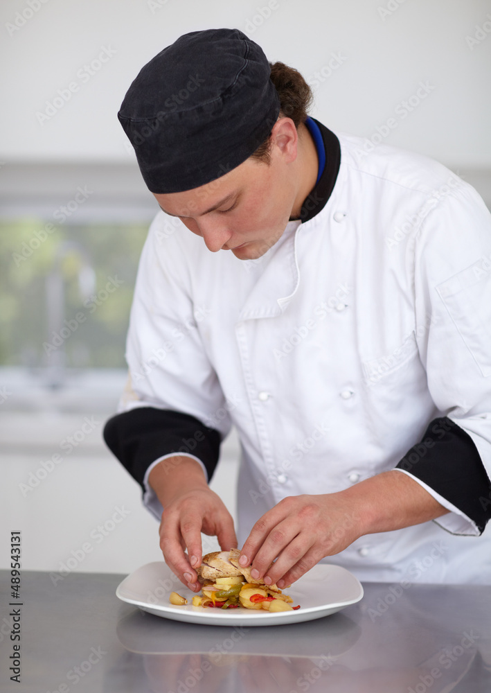 创造烹饪杰作。年轻厨师在厨房里准备一道鸡肉菜——美食。