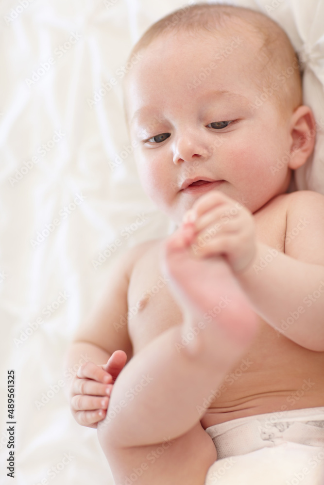 Learning through play. Sweet little baby lying down and touching its feet.