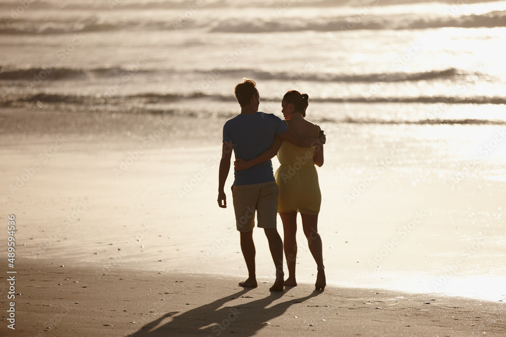 Taking an early morning walk on the beach. Shot of an affectionate couple walking on the beach.