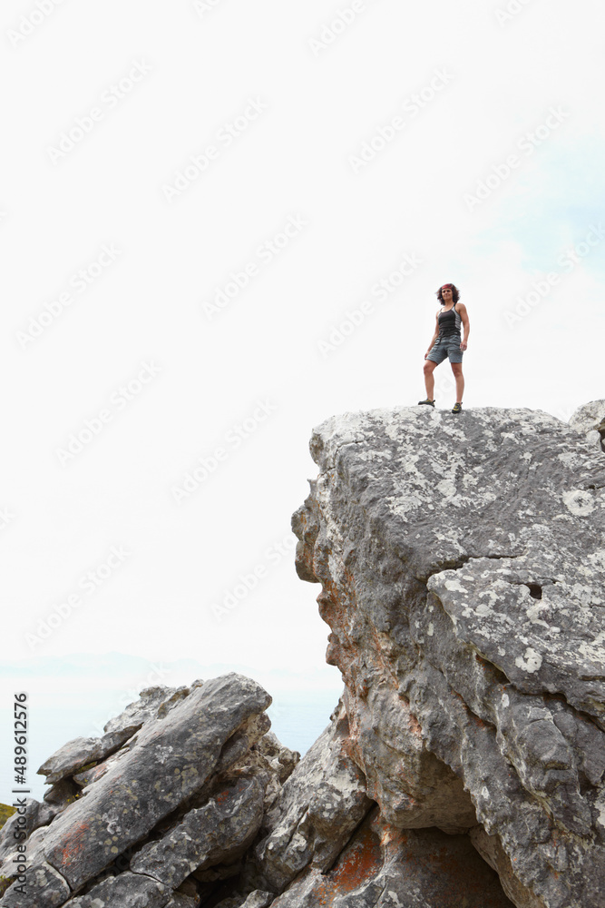 Leaving the world behind. A rock climber standing on the top of a cliff.